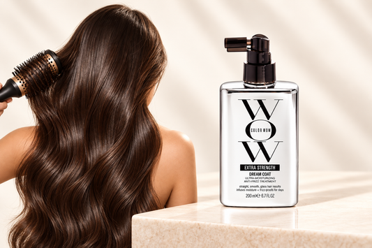 Color Wow Extra Strength Dream Coat bottle beside smooth dark hair and a round brush.