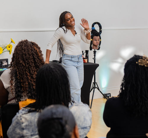 Presenter explaining a technique beside a styling mannequin.