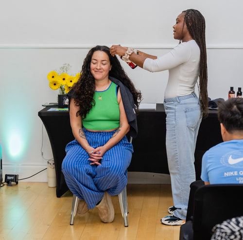 Hair care demonstration with a volunteer wearing a green top.