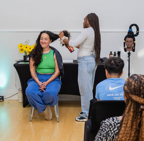 Presenter working with a volunteer's hair during a demonstration.