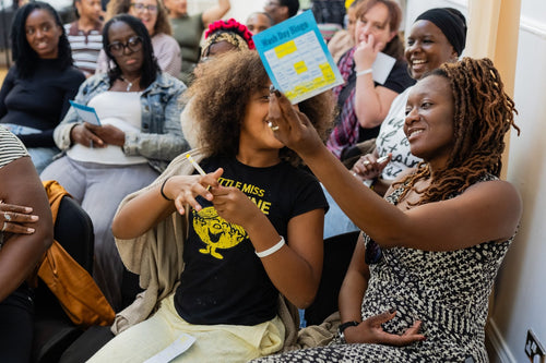 Two participants smiling and holding a colourful activity card.
