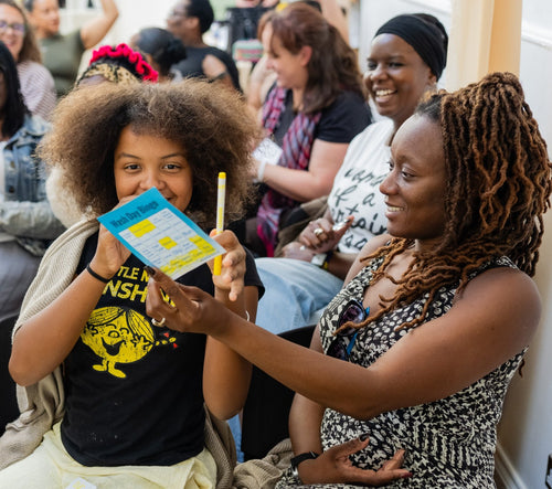 Participant holding a colourful card beside another attendee.